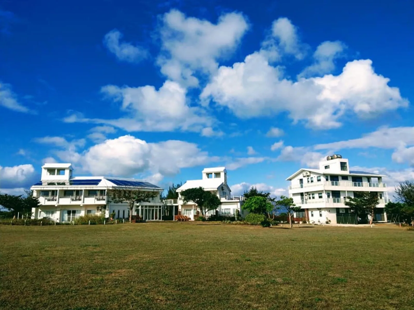 Comic B&B, Three Buildings, Blue Sky, Vast Meadow